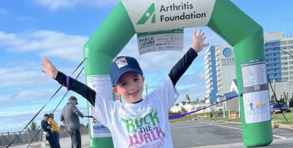 A young participant celebrates under the Arthritis Foundation Walk to Cure Arthritis arch